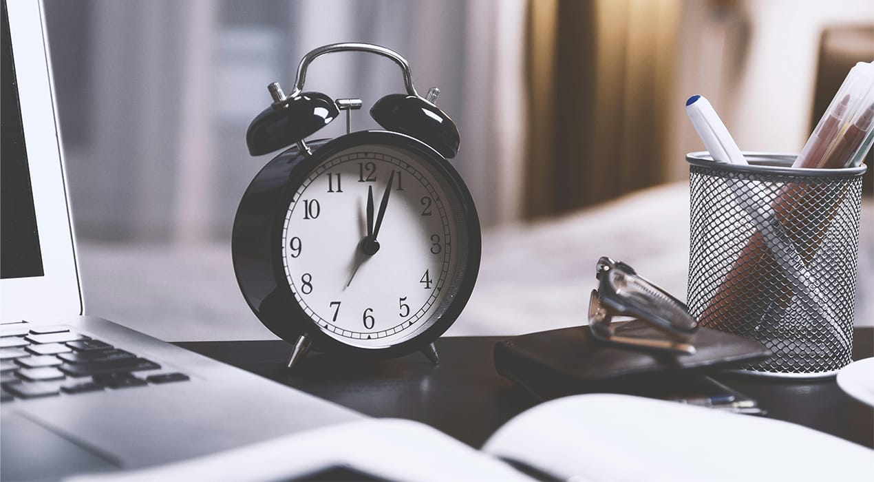 Alarm clock on desk sitting next to laptop