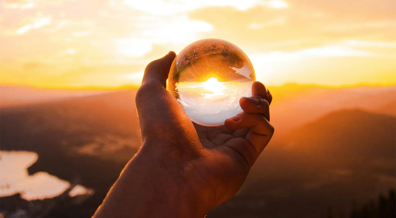 Person holding a crystal ball with a sunset in the background