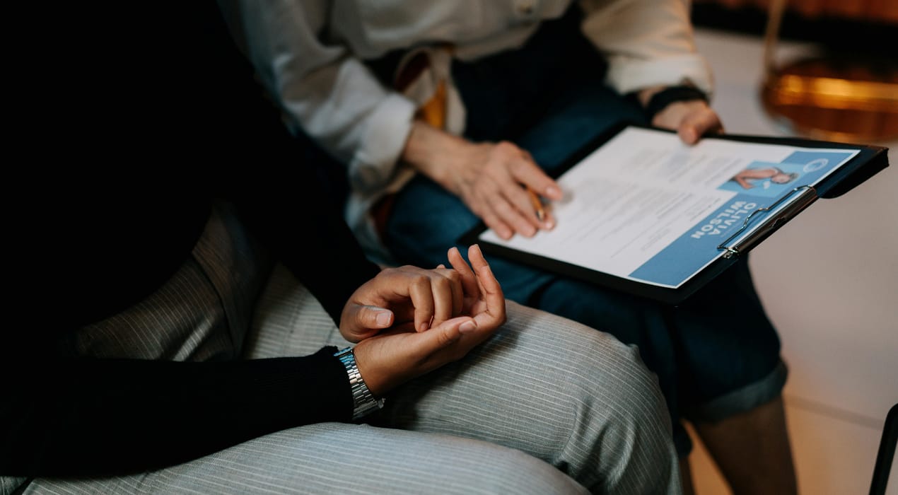 Two people sitting next to each other looking at a CV on a clipboard