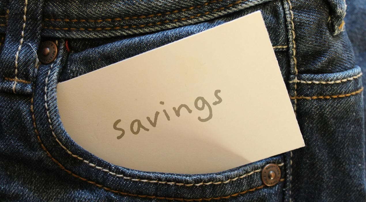 Close up of a card with "Savings" written on it, sitting in a jean pocket.