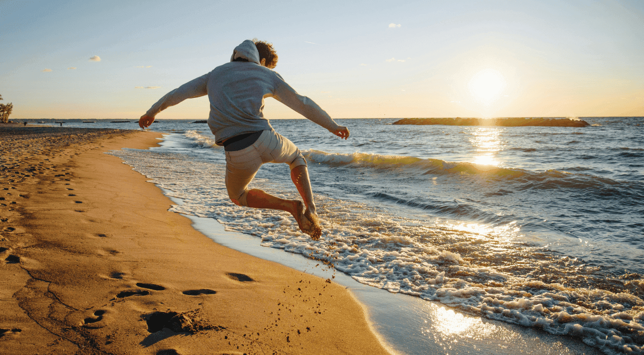 Man walking along the beach and jumping in the air