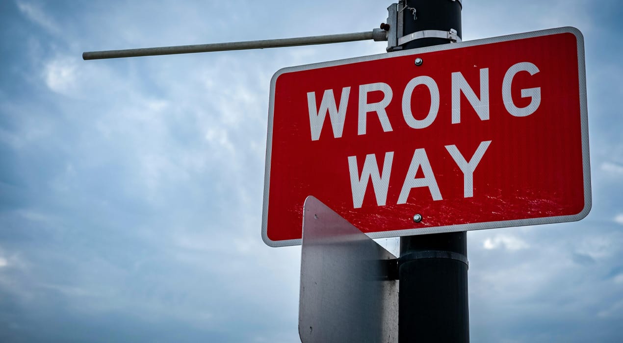 Wrong way sign against a cloudy sky