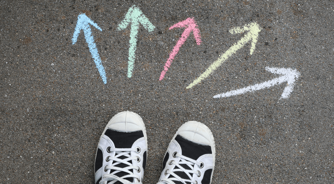Pair of shoes surrounded by different coloured chalk arrows on the ground, pointing in different directions